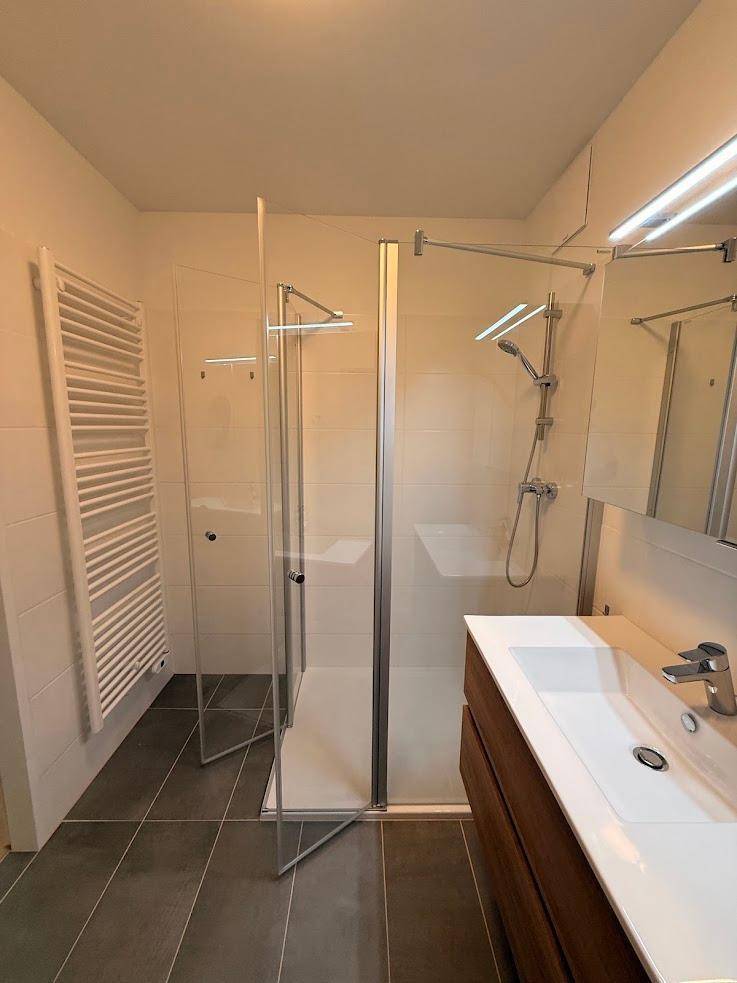 Modernes Badezimmer mit ebenerdiger Dusche, Einzelwaschbecken und beheiztem Handtuchhalter.