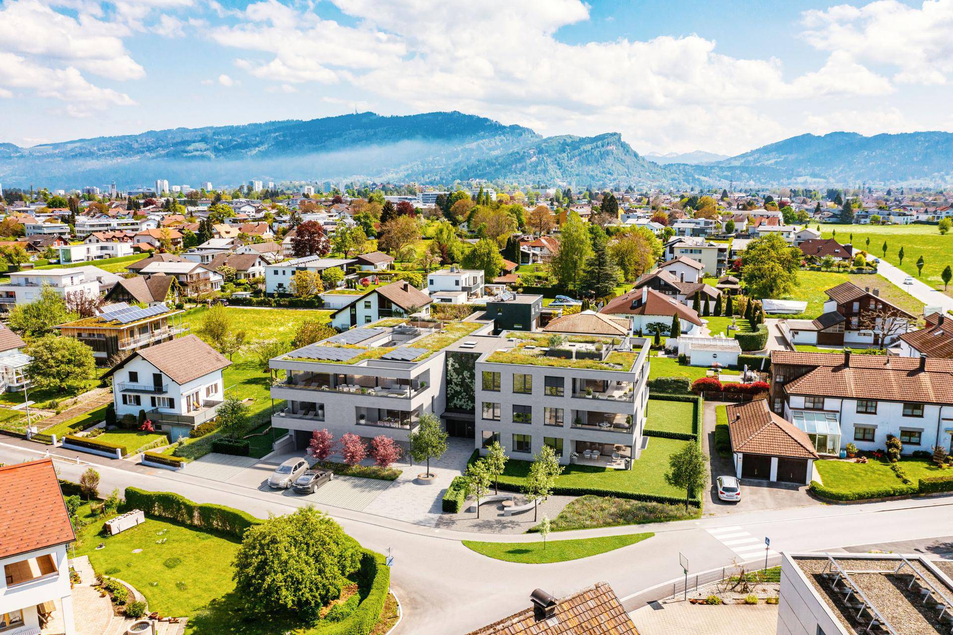 Luftaufnahme der modernen Wohngebäude eingebettet in eine grüne Wohngegend mit Bergblick.