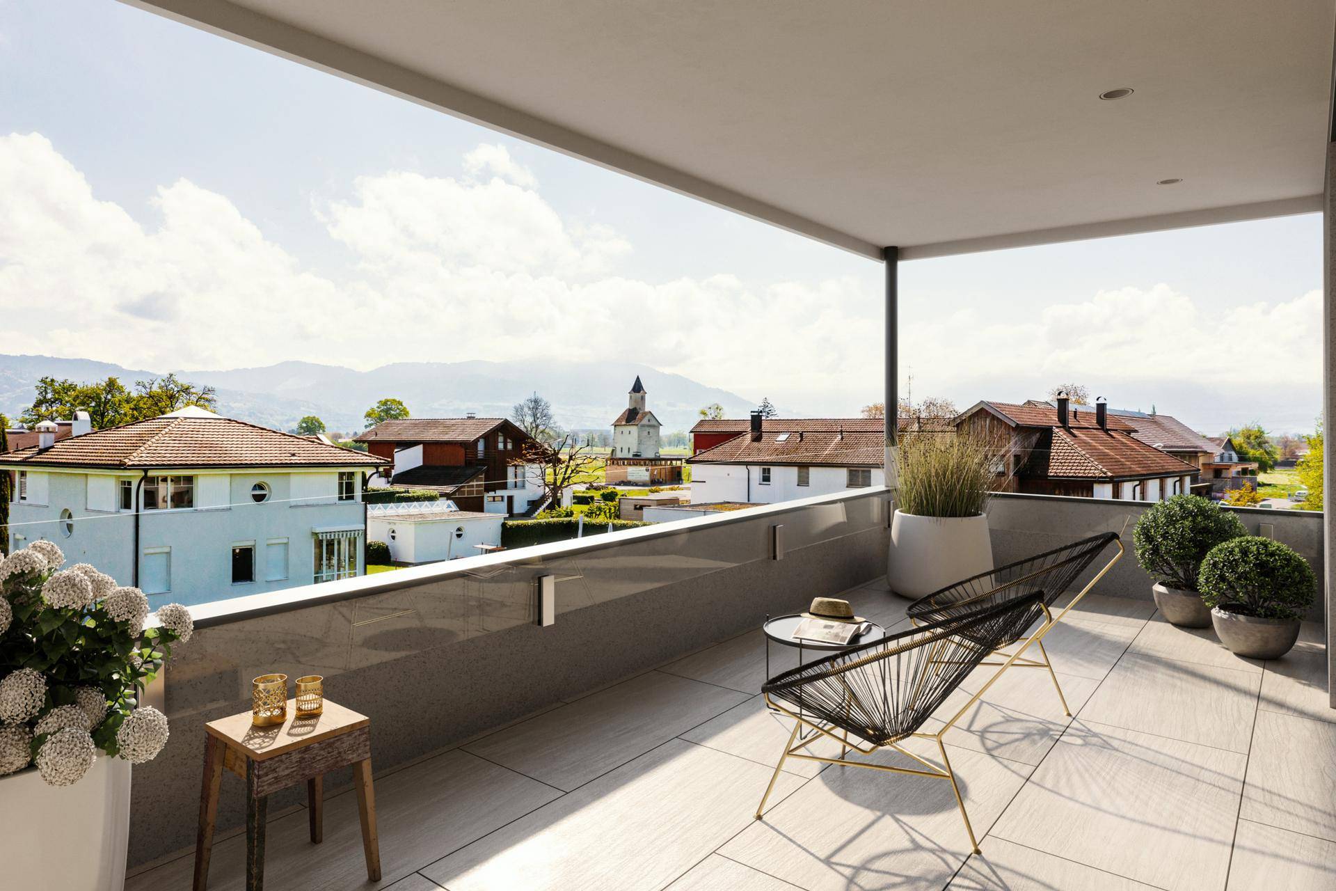 Geräumiger Balkon mit modernen Möbeln und weitem Blick über die Dächer und Berge.