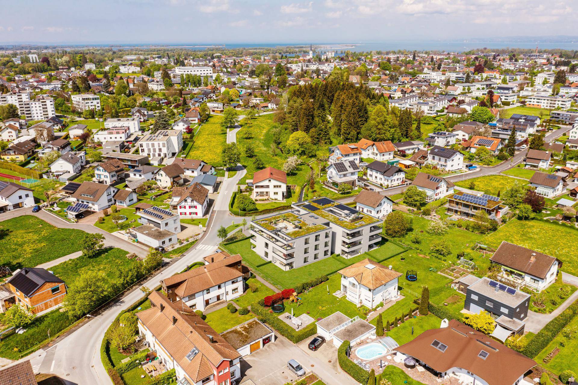 Weitläufige Luftaufnahme einer Wohnsiedlung mit Neubauten und Blick auf den Bodensee.