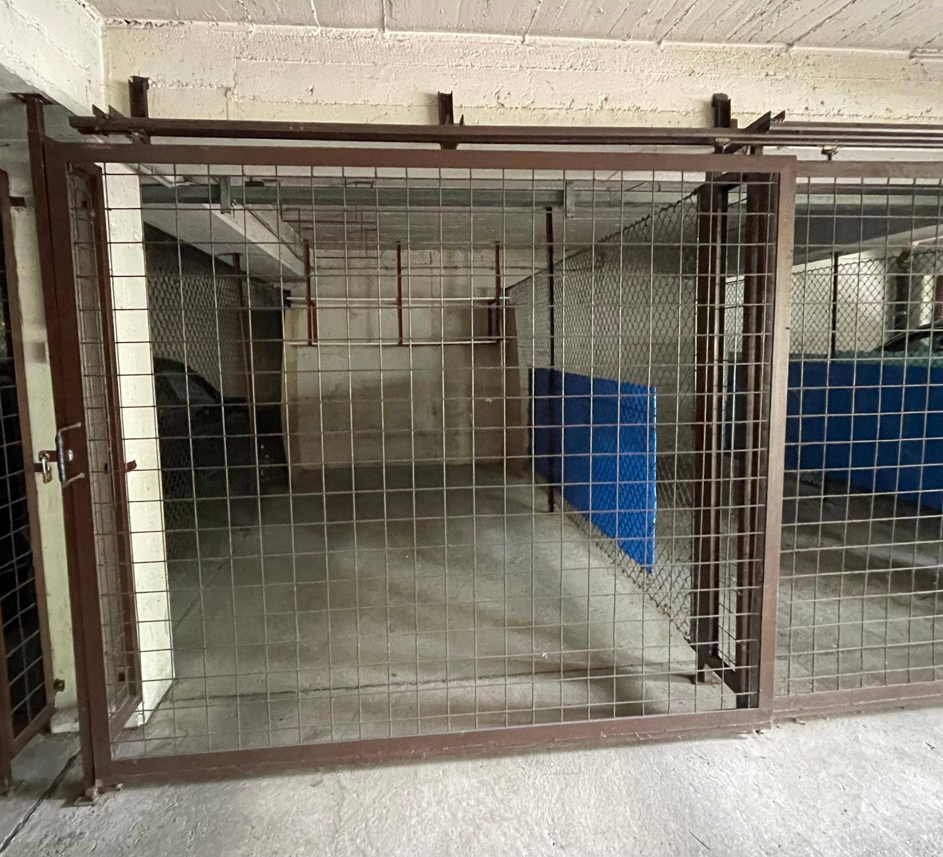Abgetrennter Lagerbereich mit Metallgittertüren in einer Tiefgarage oder einem Keller.