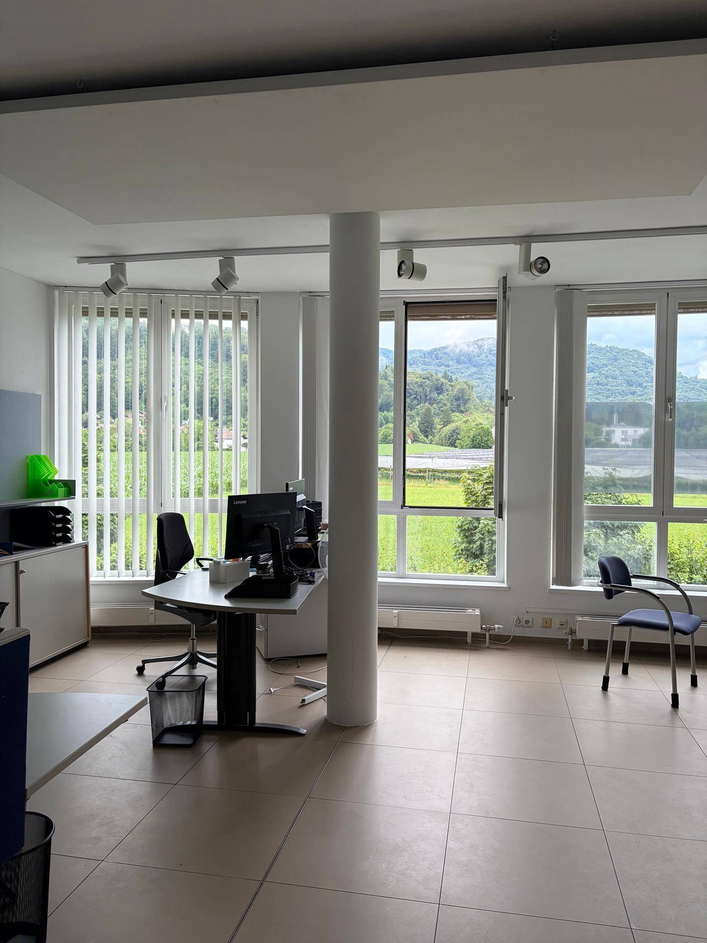 Helles Büro mit großen Fenstern, die einen weiten Blick ins Grüne bieten und modernen Arbeitsplätzen.
