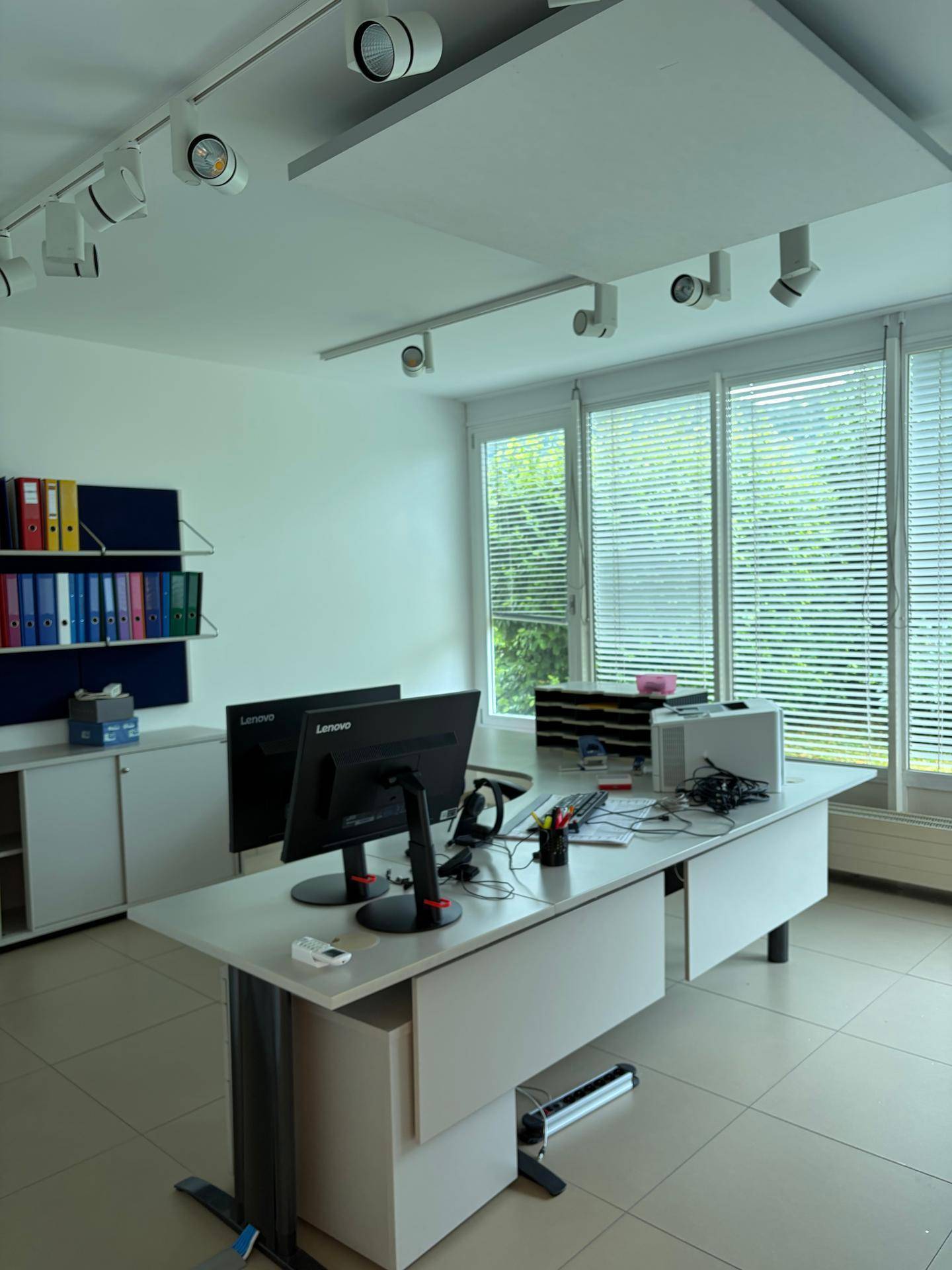 Modern eingerichtetes Büro mit mehreren Arbeitsplätzen, großen Fenstern und guter Beleuchtung.