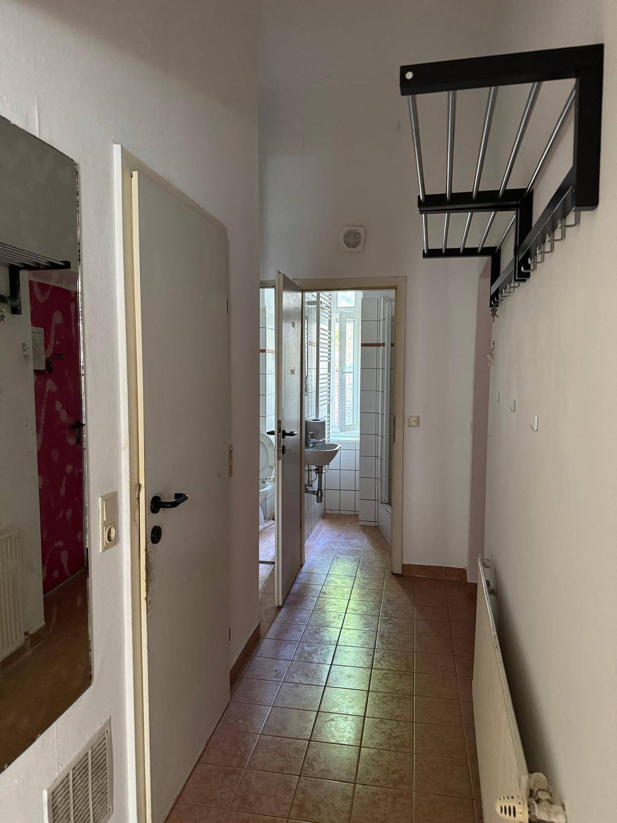 Heller Flur mit Fliesenboden, Garderobe und Zugang zu weiteren Räumen, inklusive Badezimmer.