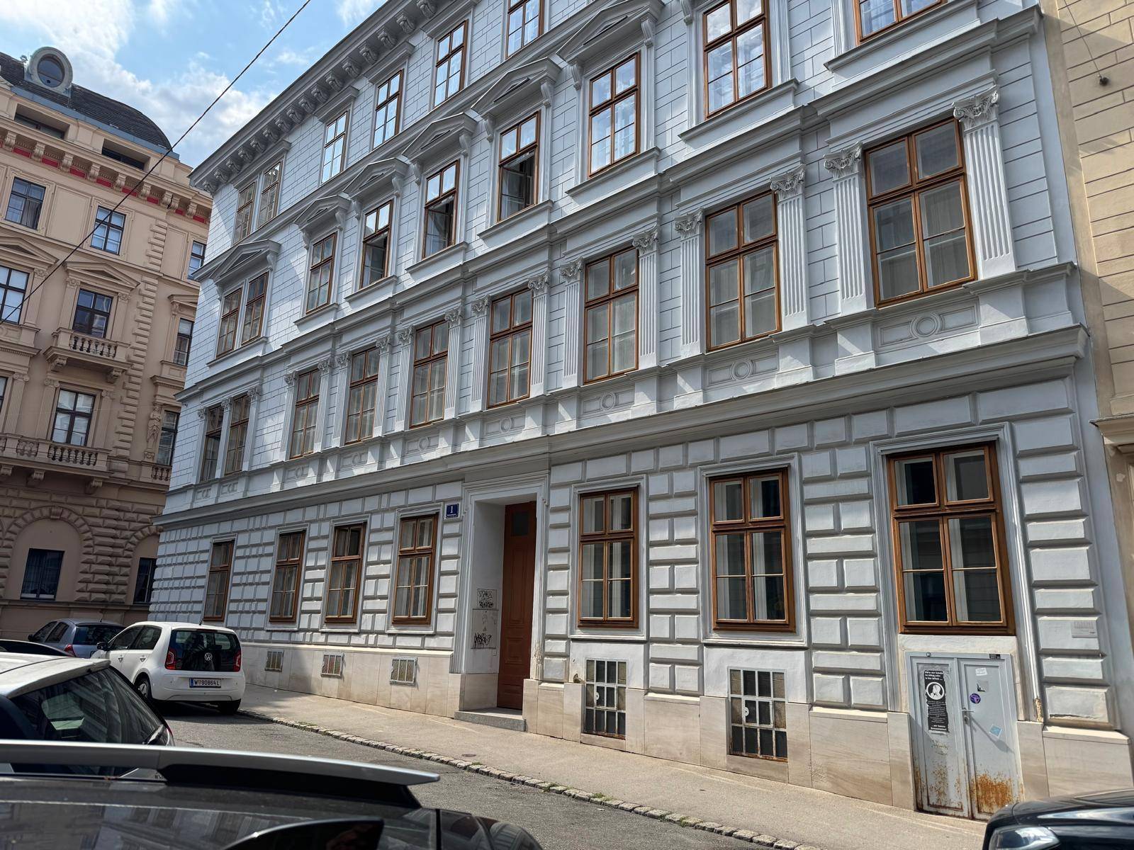 Historisches Gebäude mit klassischer Fassade und vielen Fenstern an einer belebten Stadtstraße.