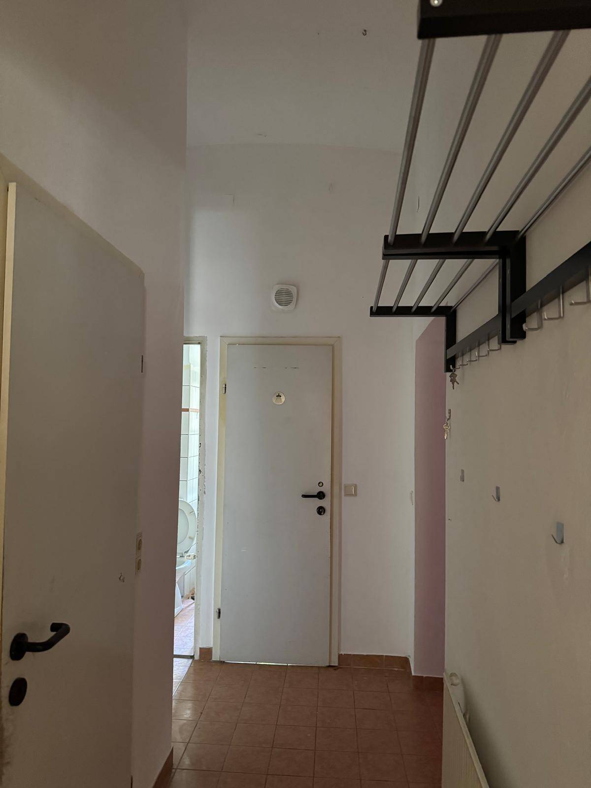 Langer Flur mit Fliesenboden und Garderobe, der zu verschiedenen Zimmern führt.