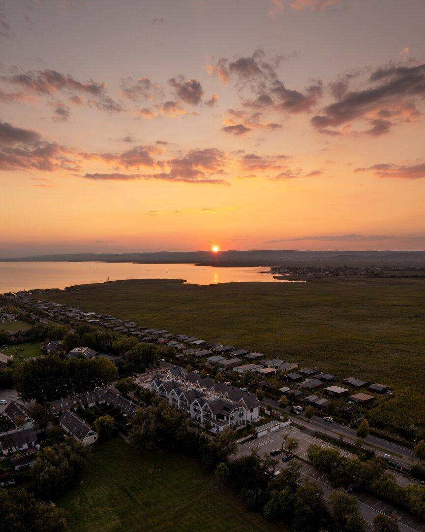Panoramablick auf die Wohnanlage bei Sonnenuntergang mit malerischem See und weitem Horizont.