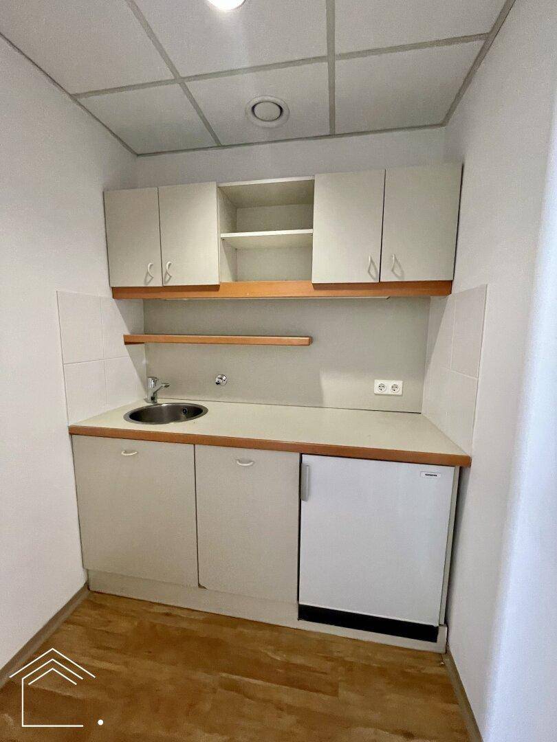 Kompakte Küchenzeile mit Spüle, Unterschränken und Kühlschrank, ideal für kleine Büros.