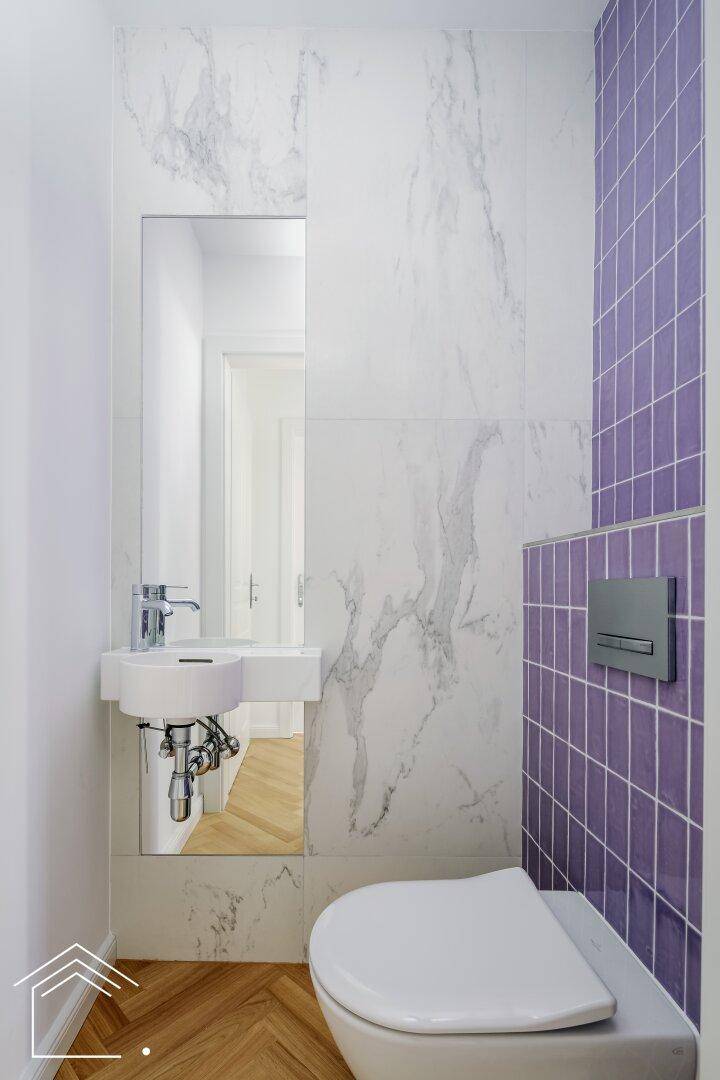 Modernes Gäste-WC mit lila Fliesen, kleinem Waschbecken und Wandspiegel.