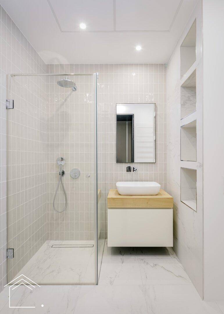 Modernes Badezimmer mit begehbarer Dusche, Einzelwaschbecken und hellen Fliesen.