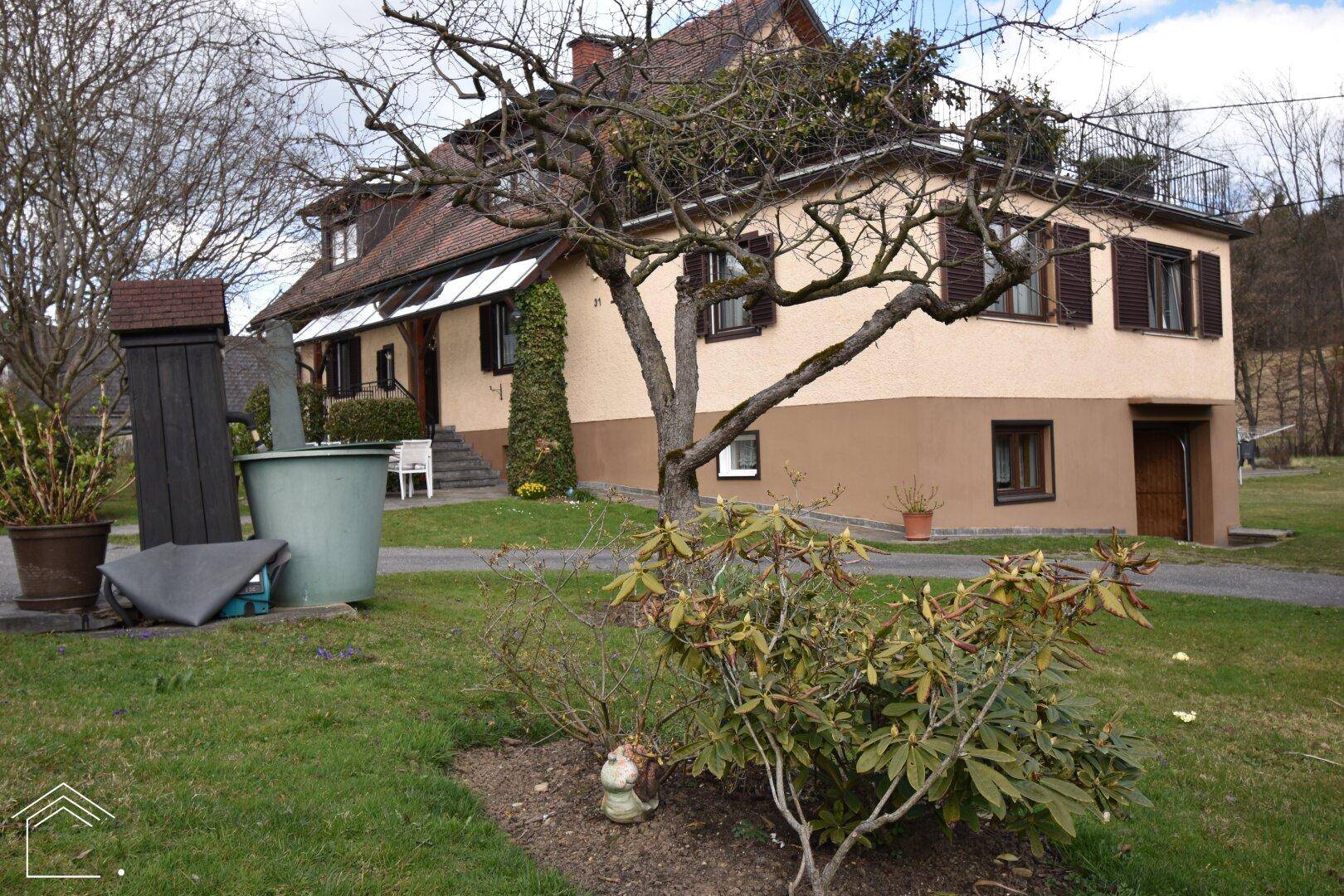 Seitenansicht des Hauses mit Garten und Bäumen, die die ländliche Idylle unterstreichen.