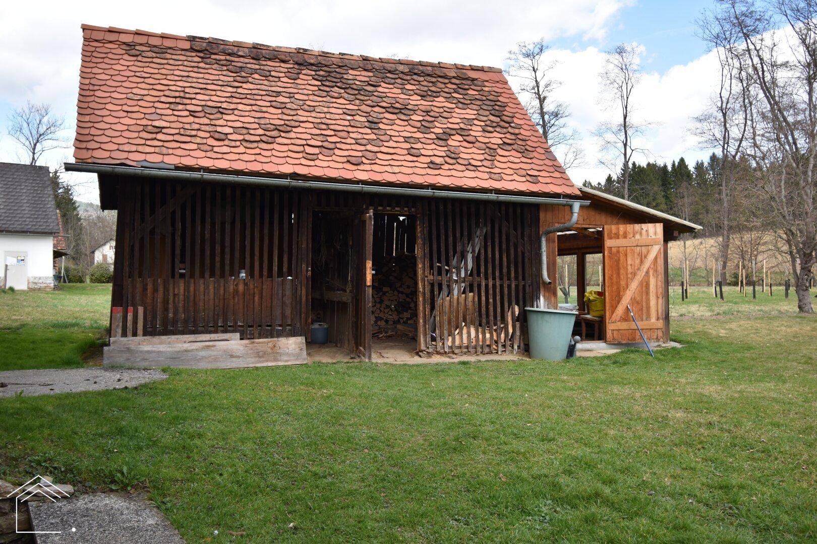 Rustikale Holzscheune mit Satteldach im weitläufigen Gartenbereich, ideal für Lagerung.
