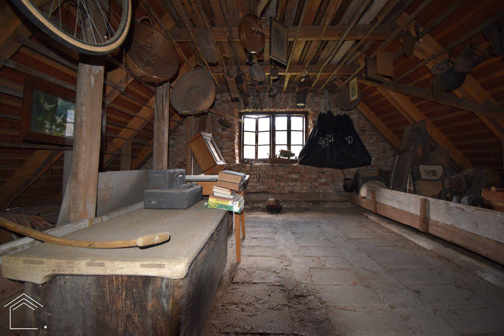 Geräumiger Dachboden mit sichtbaren Holzbalken und Fenster, bietet Ausbaupotenzial.