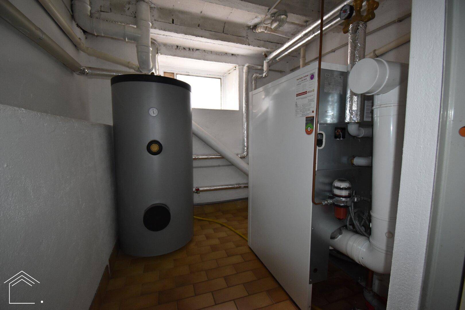Heizungsraum im Keller mit modernem Warmwasserspeicher und Heizungsanlage.
