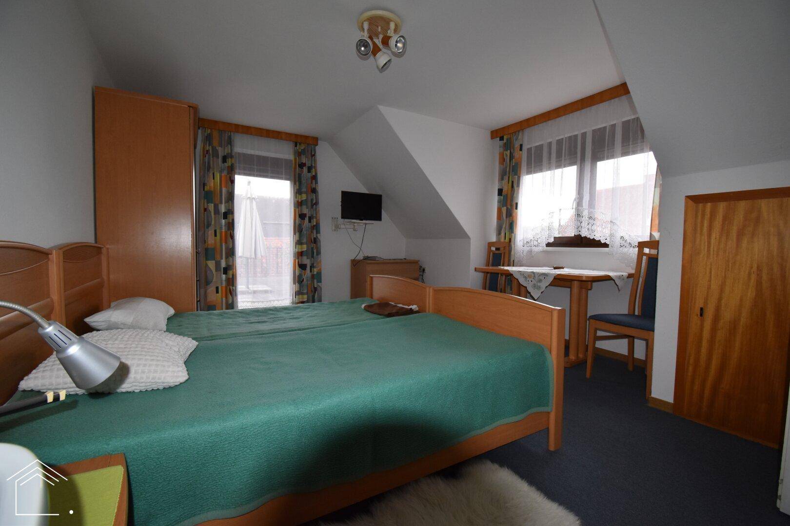 Gemütliches Schlafzimmer mit zwei Einzelbetten und einem kleinen Tisch unter dem Fenster.