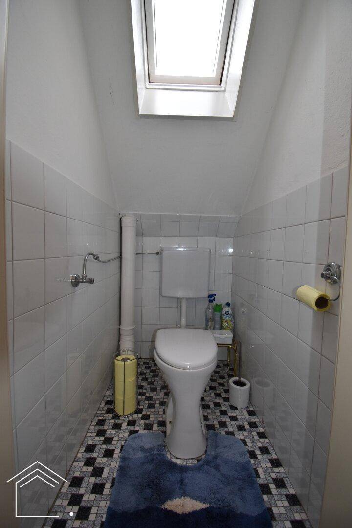 Separate Toilette mit Dachfenster, das für natürliches Licht sorgt, und Fliesenboden.