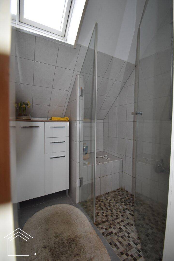 Modernes Badezimmer mit begehbarer Dusche, Dachschräge und Dachfenster für Helligkeit.