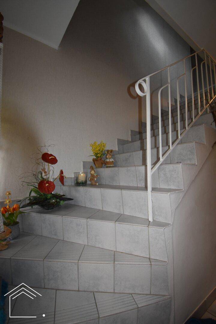 Geflieste Treppe mit Geländer, die die verschiedenen Etagen des Hauses verbindet.