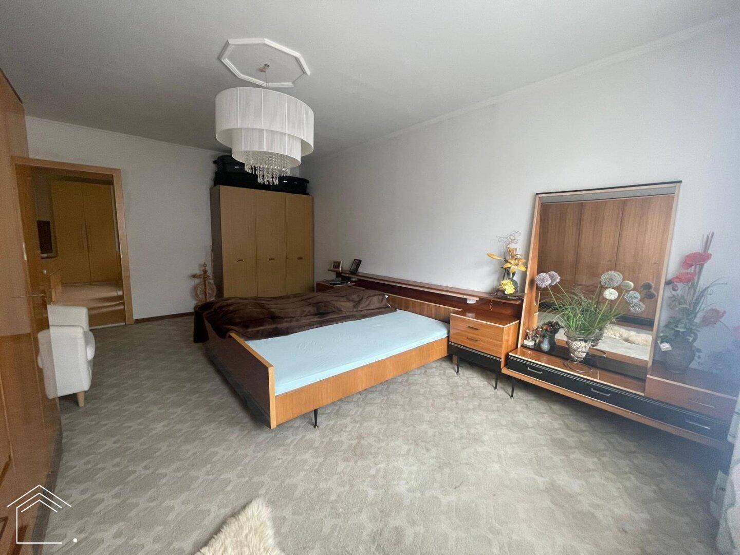 Geräumiges Schlafzimmer mit Doppelbett, klassischer Holzmöblierung und Teppichboden.