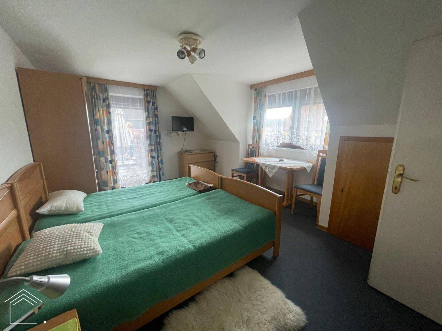 Schlafzimmer mit zwei Einzelbetten und Dachschräge, die eine behagliche Atmosphäre schafft.