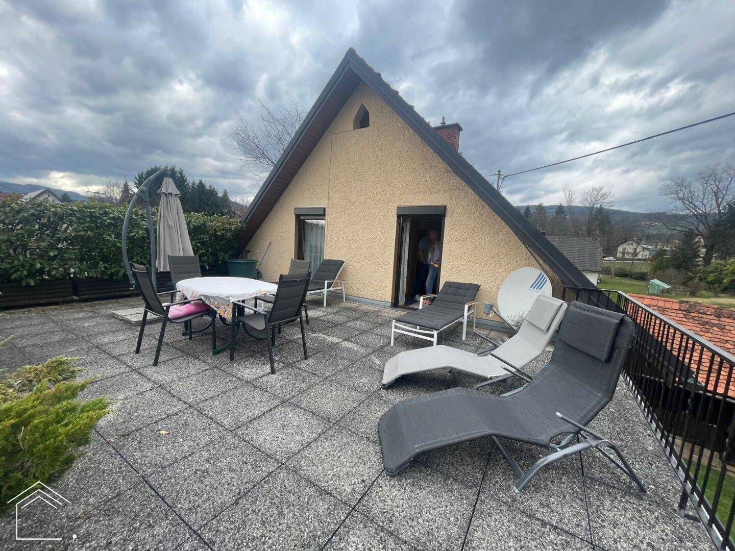 Geräumige Dachterrasse mit Fliesenboden, Liegestühlen und weitem Blick über die Landschaft.
