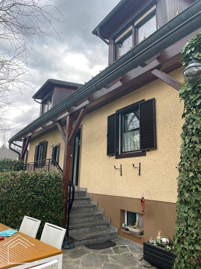 Der Hauseingangsbereich mit einer kleinen, gepflasterten Terrasse und Sitzgelegenheiten.