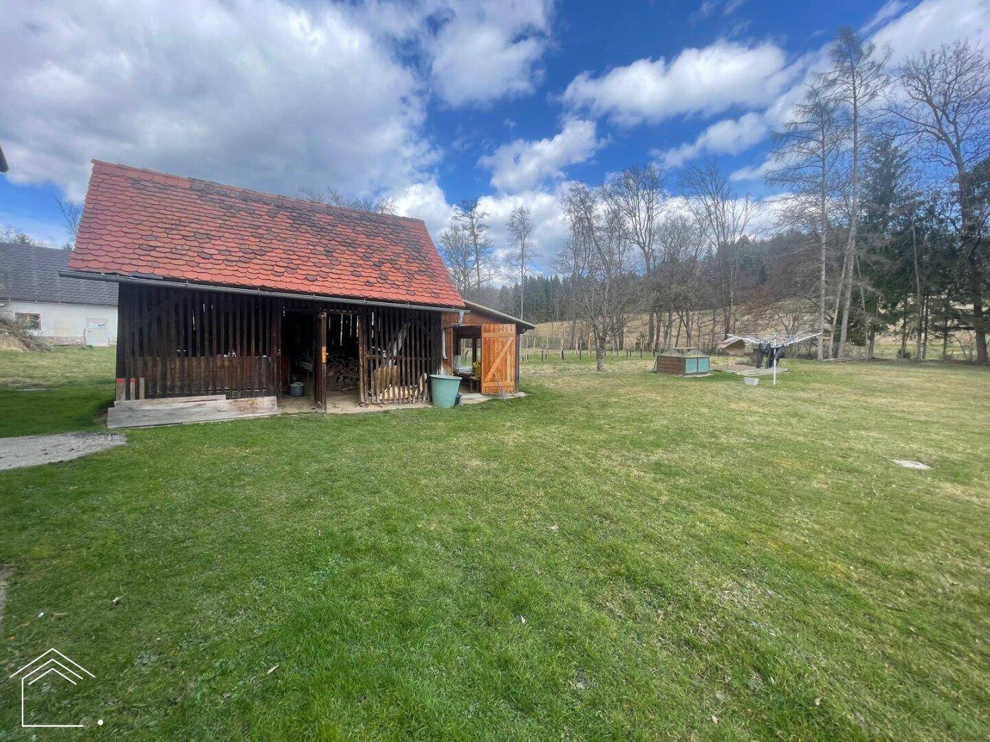 Große Gartenfläche mit Scheune und ländlichem Ausblick, umgeben von Natur.
