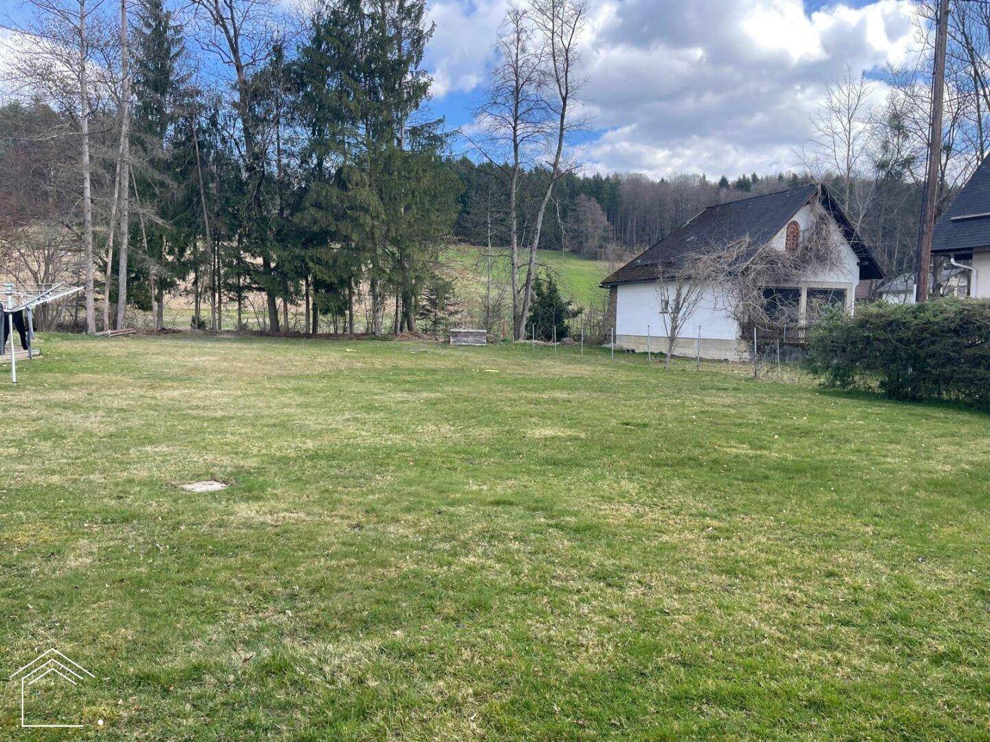 Weitläufige Rasenfläche mit Blick auf die Umgebung und die umliegenden Wälder.