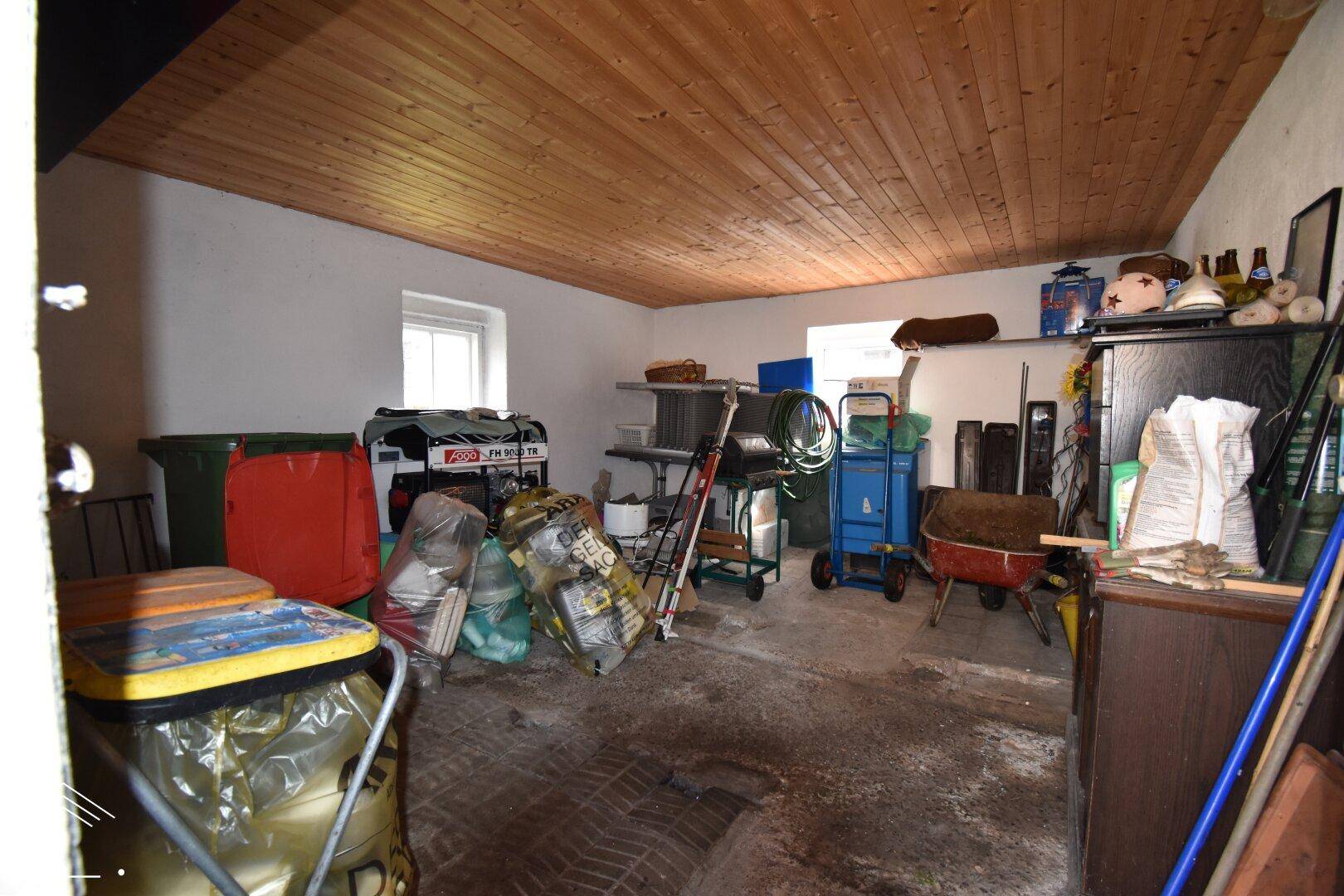 Abstellraum mit verschiedenen Geräten und einer Holzdecke, bietet viel Stauraum.