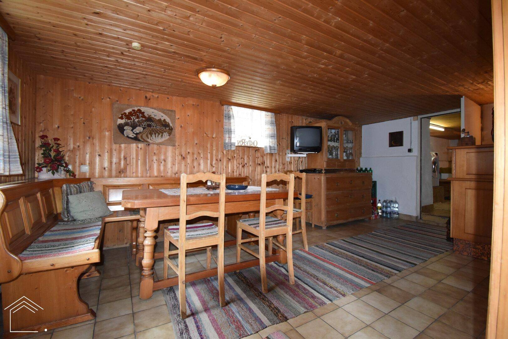 Gemütlicher Kellerraum mit Holzvertäfelung, Essbereich und Fliesenboden, vielseitig nutzbar.