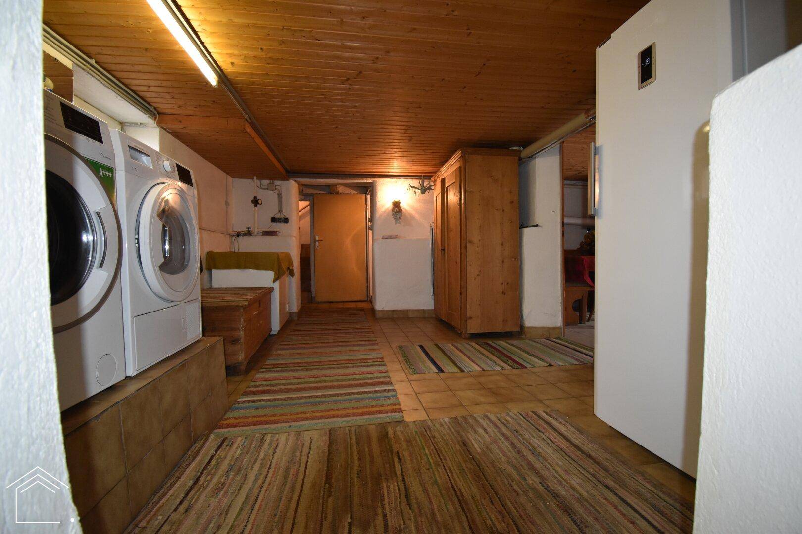 Funktionaler Waschraum im Keller mit Waschmaschinen und Trockner für den täglichen Bedarf.