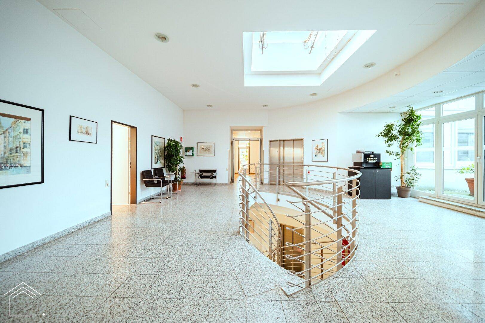 Heller Flur im Obergeschoss mit geschwungener Treppe, Oberlicht und Zugang zu weiteren Büroräumen.
