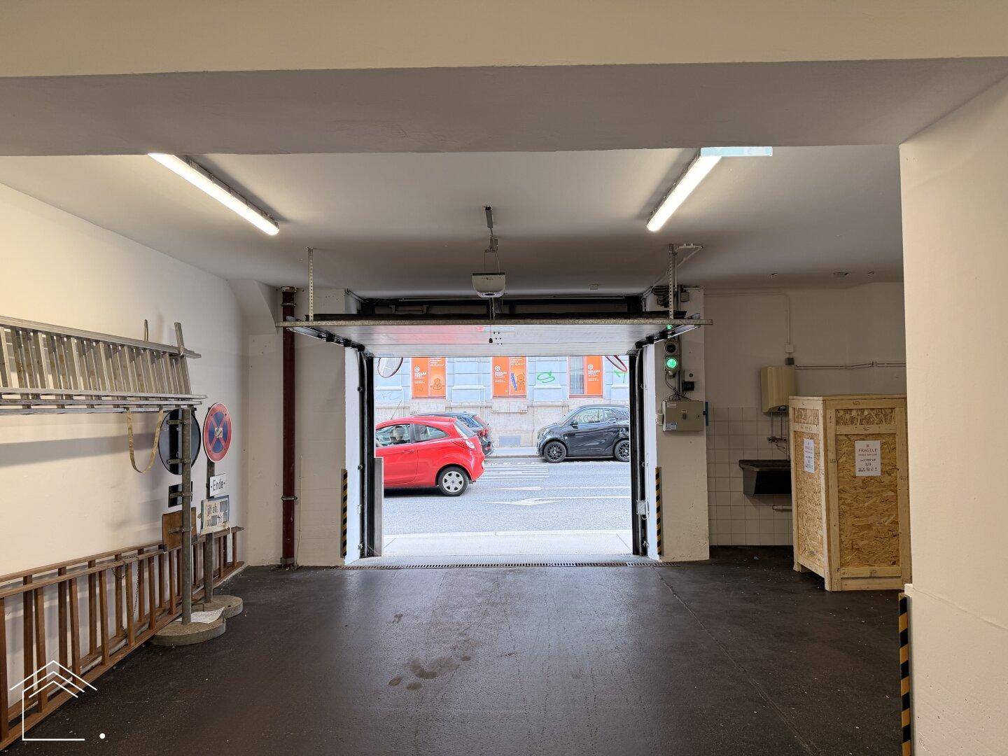 Einfahrt zur Tiefgarage von innen gesehen, mit Blick auf die Straße und geparkte Autos.