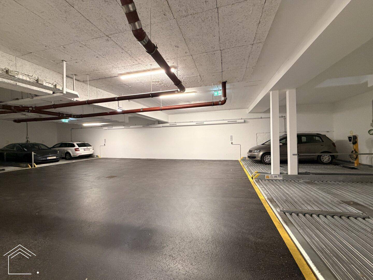 Geräumige Tiefgarage mit mehreren Stellplätzen und einem Doppelparker-System für Fahrzeuge.