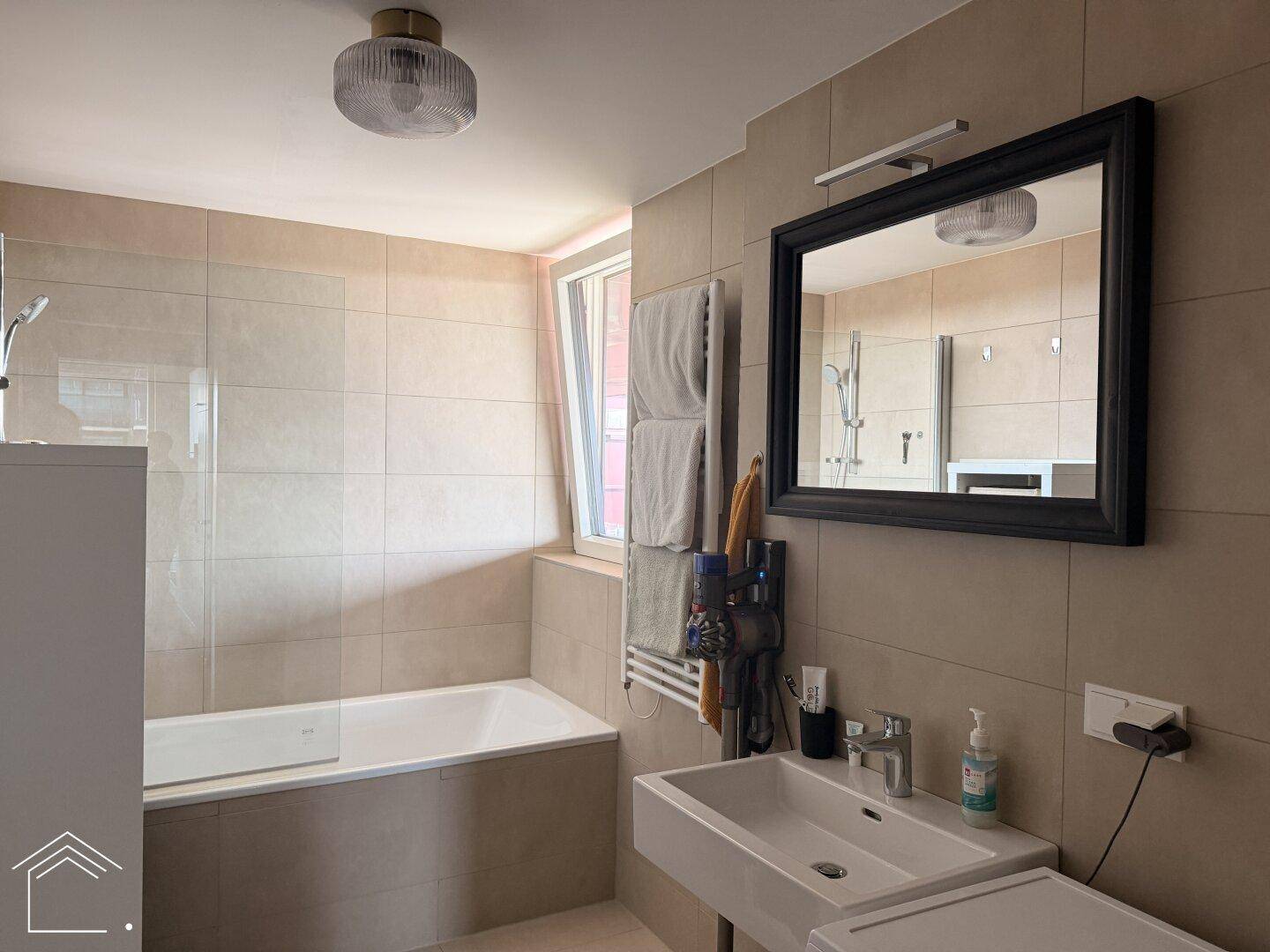 Helles Badezimmer mit Badewanne, modernem Waschbecken und großem Spiegel, gut beleuchtet.