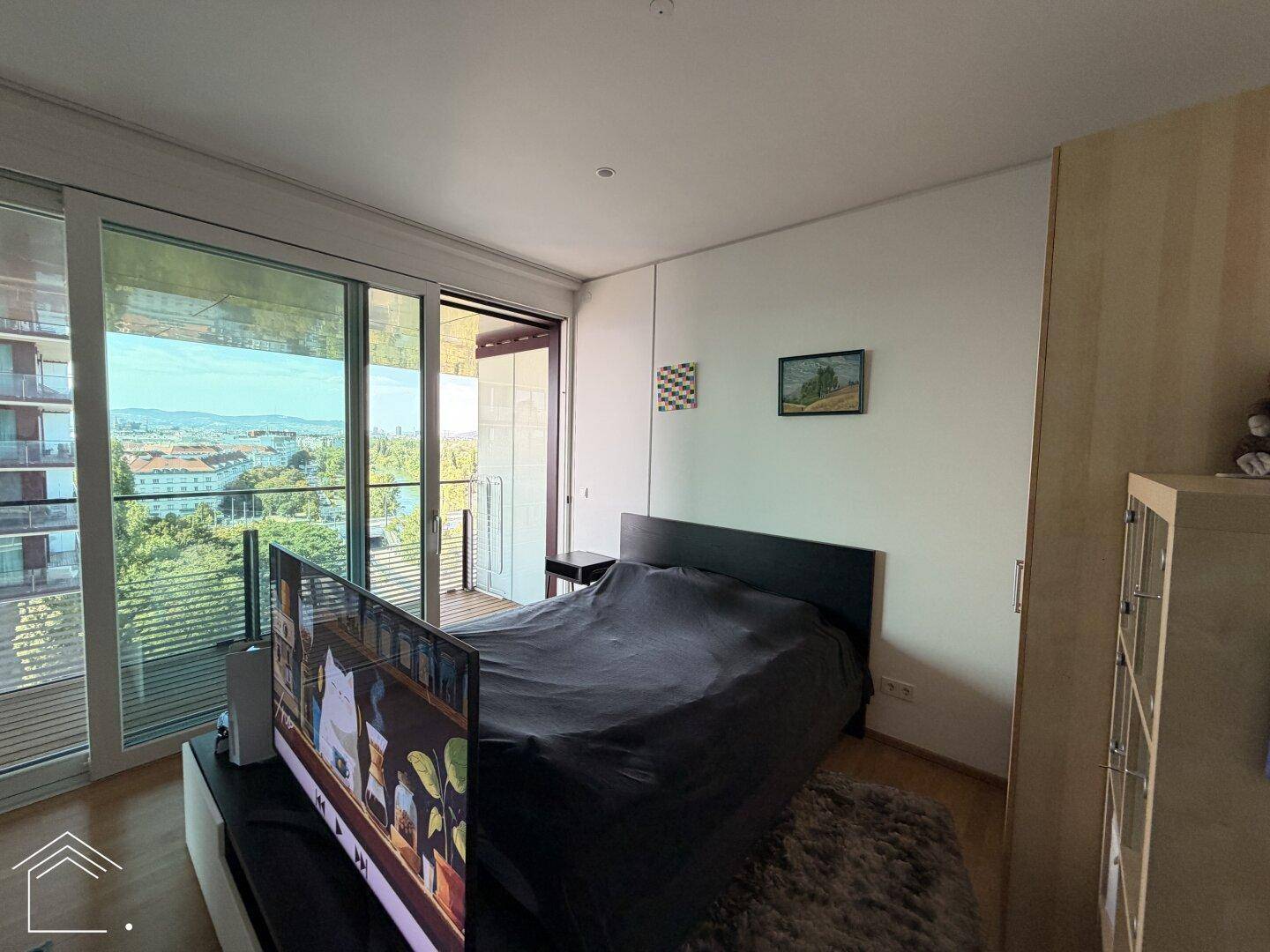 Helles Schlafzimmer mit großem Bett, Fernseher und Zugang zu einem Balkon mit schöner Aussicht.