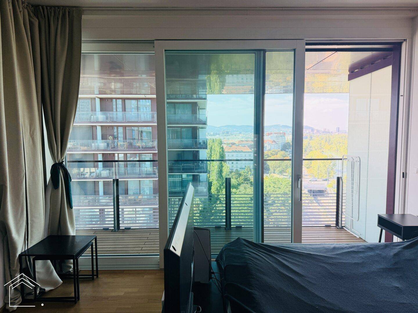 Große Fensterfront mit Schiebetüren zum Balkon, die viel Licht hereinlässt und eine weite Aussicht bietet.