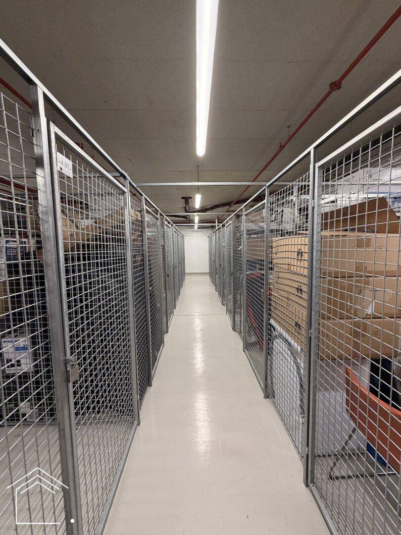 Kellerabteil mit Gitterboxen für zusätzlichen Stauraum, gut beleuchtet und organisiert.