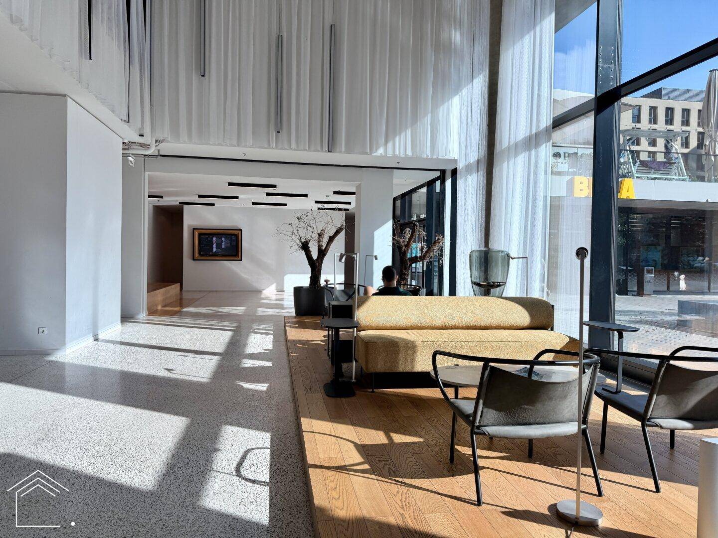 Helles und modernes Foyer mit großen Fenstern, bequemen Sitzmöbeln und Blick nach draußen.