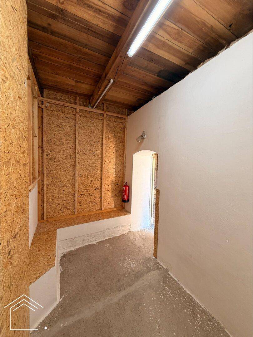 Lagerraum mit OSB-Platten, Holzdecke, Betonboden und einem Feuerlöscher an der Wand.
