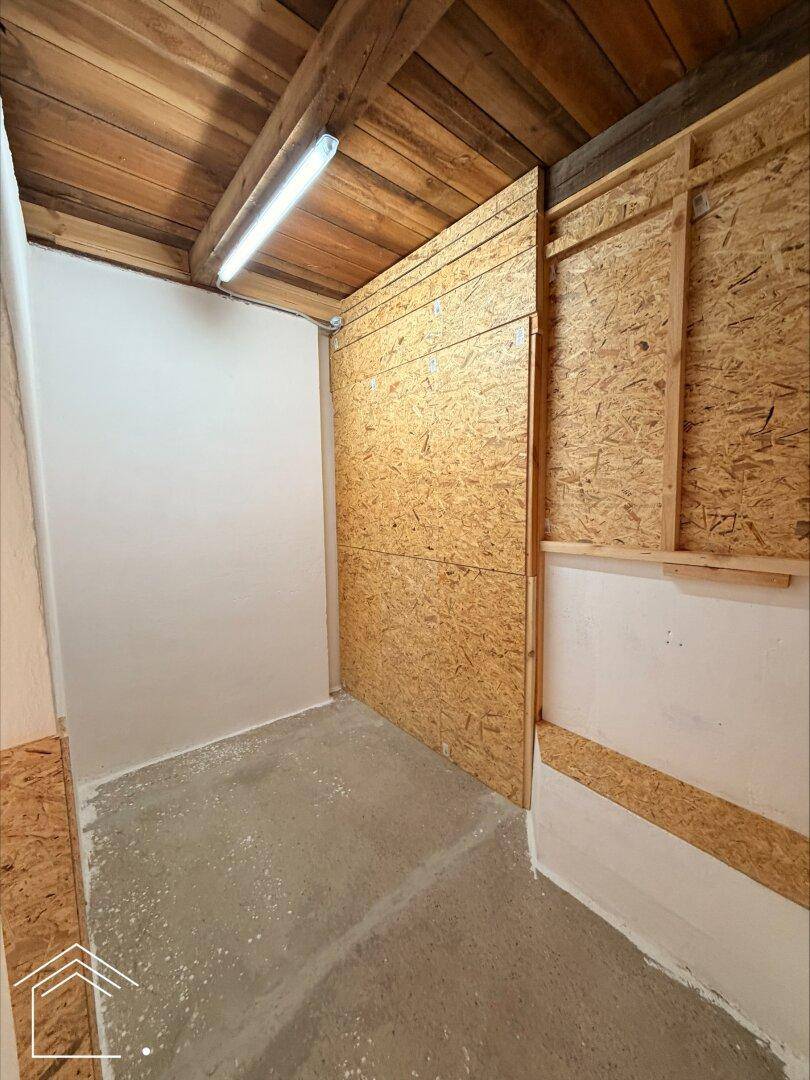 Ecke eines Lagerraums mit OSB-Plattenverkleidung, Holzdecke und schlichtem Betonboden.