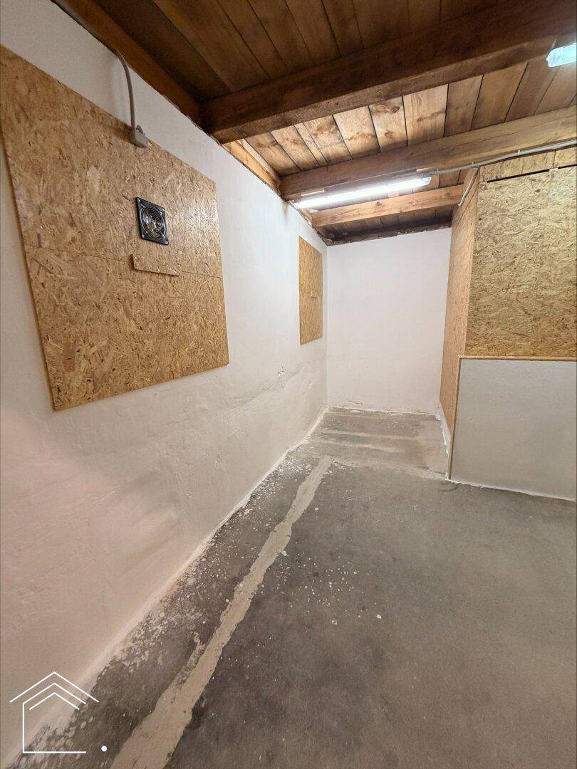 Innenansicht eines Lagerraums mit teilweise verputzten Wänden, OSB-Platten und Holzdecke.