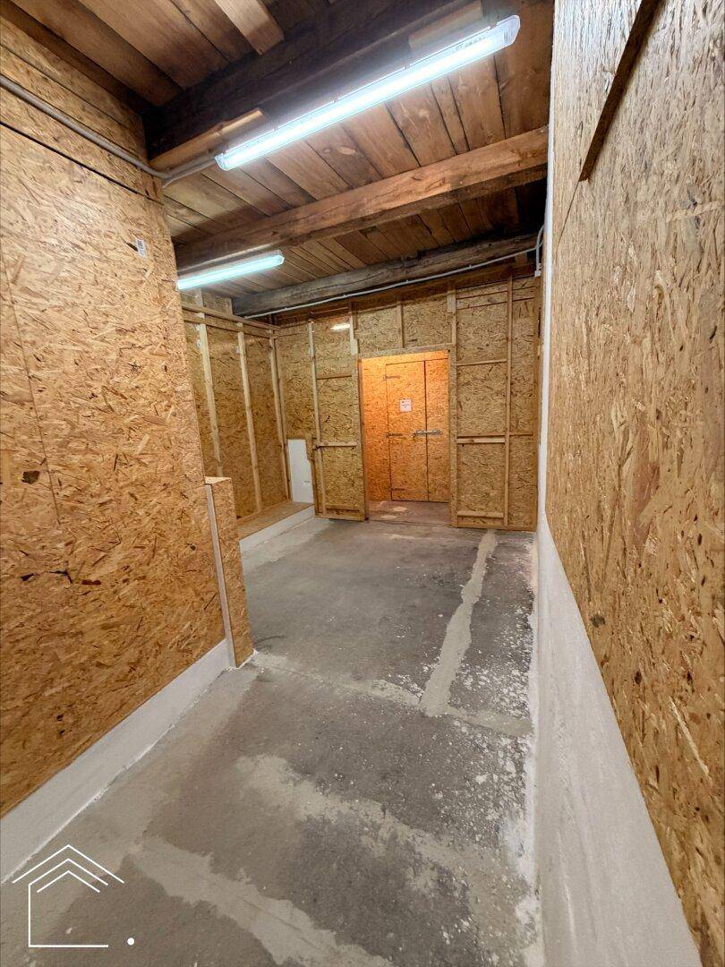 Blick in einen größeren Lagerbereich mit OSB-Wänden, Holzdecke und Betonboden.