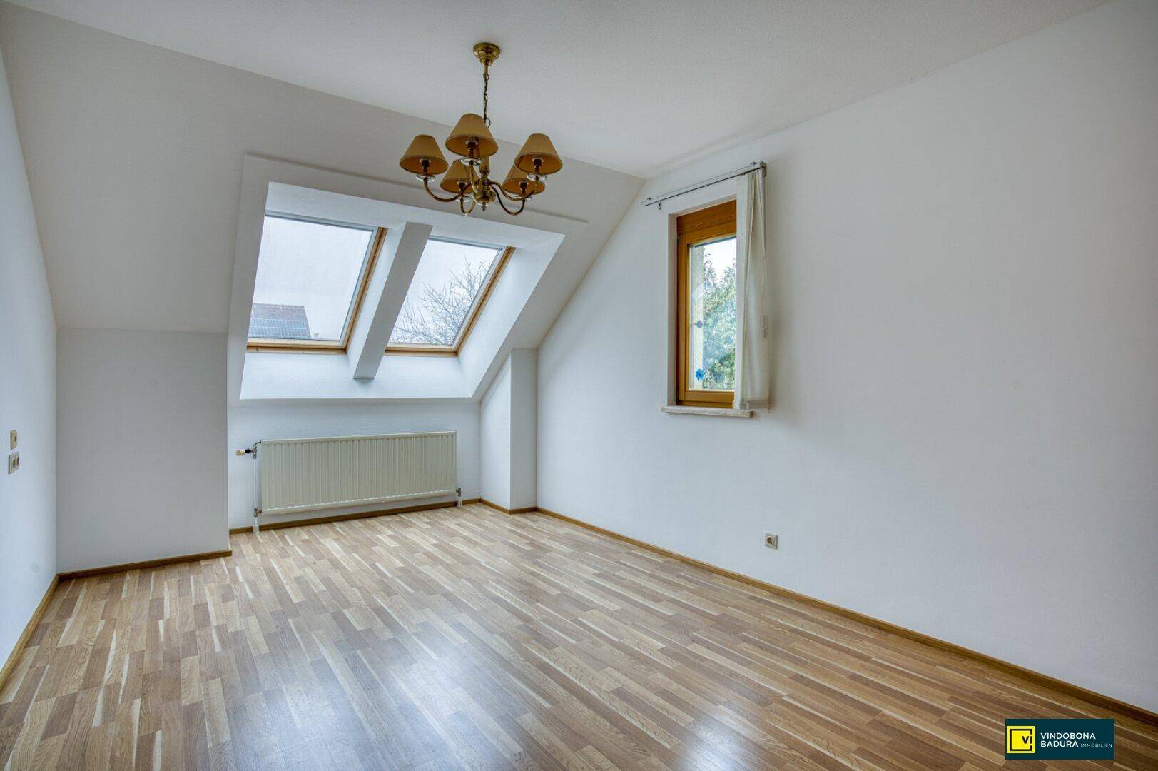 Geräumiges Dachzimmer mit Laminatboden, Dachfenstern und viel natürlichem Licht.