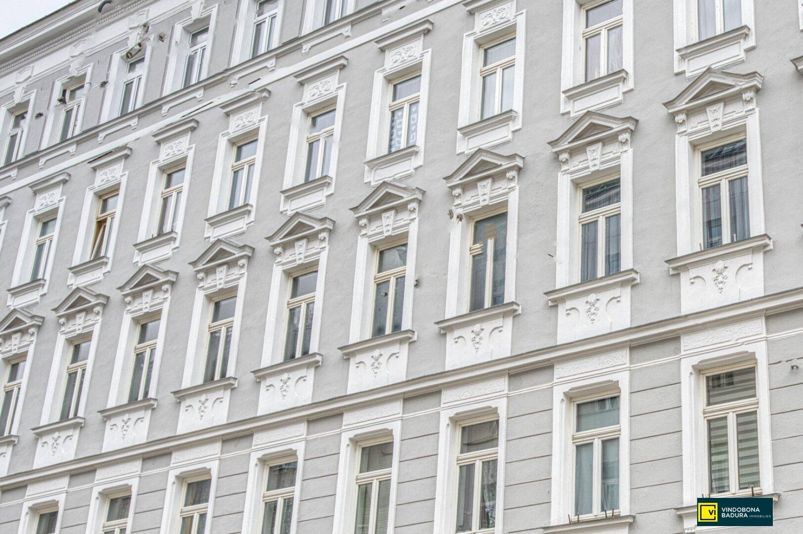 Klassische Altbaufassade mit vielen Fenstern und dekorativen Stuckelementen, typisch für städtische Architektur.