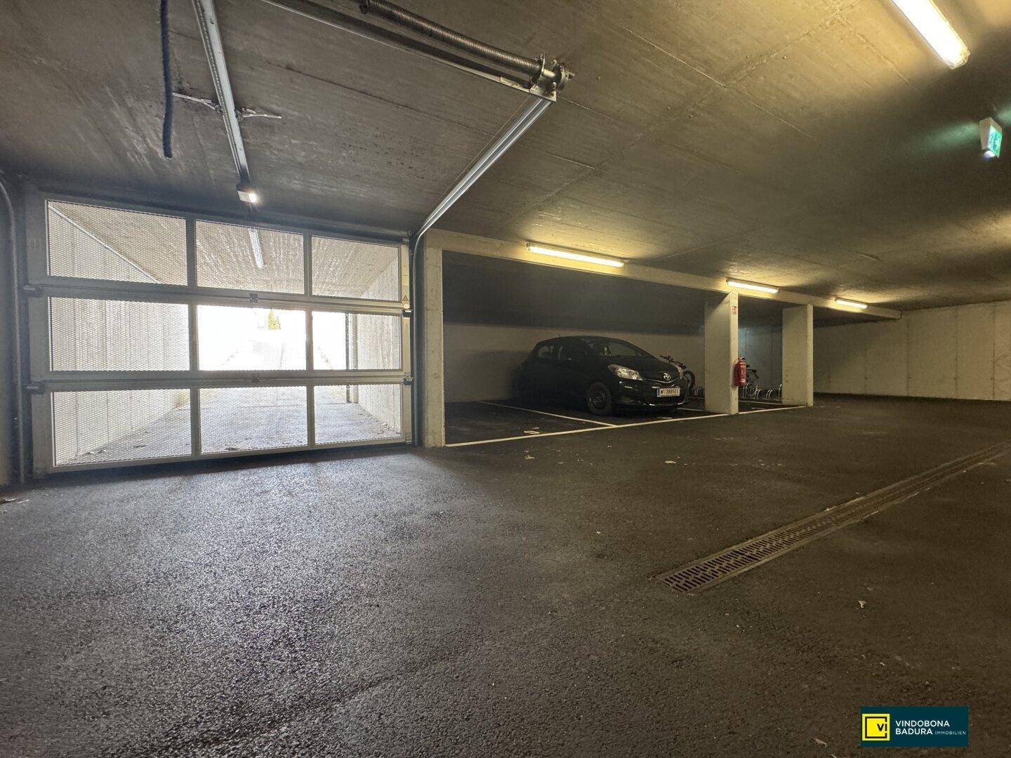 Garagenstellplatz in der Tiefgarage mit einem geparkten Auto und Blick auf die Ausfahrt.