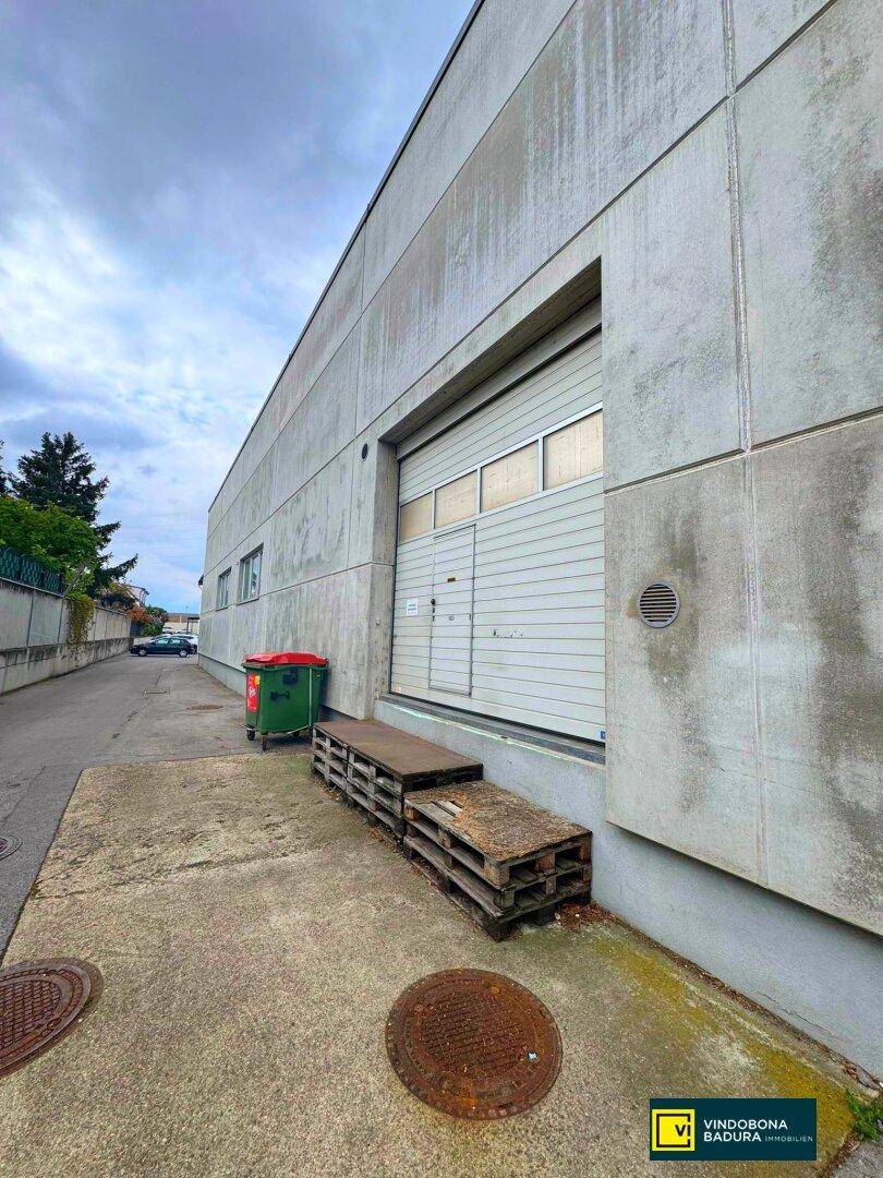 Seitenansicht eines Industriegebäudes mit großem Rolltor und Laderampe für Warenlieferungen.