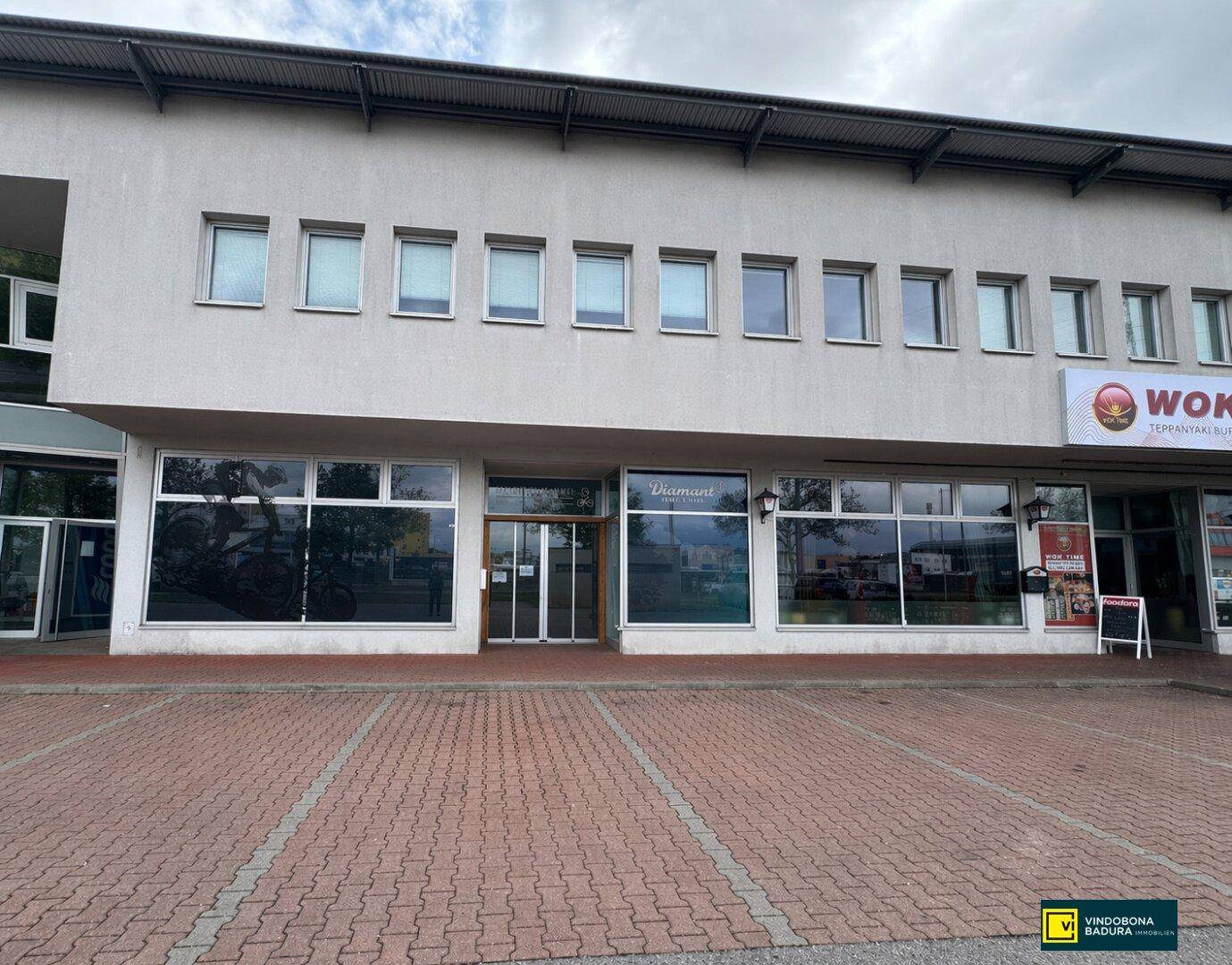 Fassade eines Geschäftsgebäudes mit großen Schaufenstern und darüber liegenden Büroräumen.