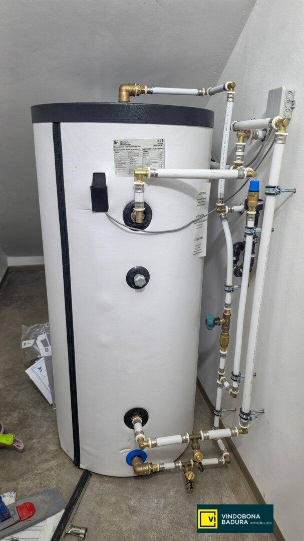 Warmwasserspeicher mit sichtbaren Rohrleitungen in einem Technikraum.