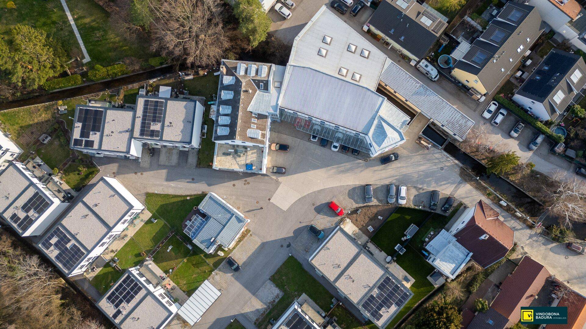 Weitläufige Luftaufnahme des gesamten Areals mit mehreren Gebäuden und Solaranlagen auf den Dächern.